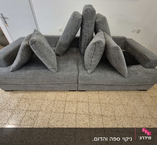 ספה אפורה עם כריות מונחות על רצפה מרוצפת